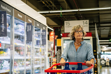 Senior woman shopping groceries in supermarket aisle