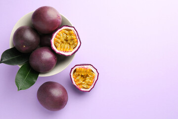 Fresh passion fruits with green leaves on violet background, flat lay. Space for text