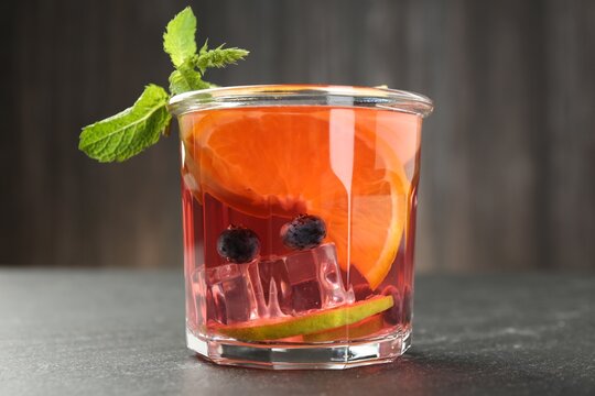 Tasty fruity punch in glass on dark gray textured table, closeup
