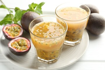 Tasty passion fruit drink and fresh fruits on white wooden table, closeup