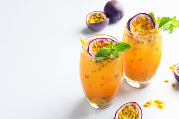 Tasty passion fruit drink with mint in glasses and fresh fruits on white table. Space for text
