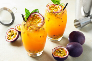 Tasty passion fruit drink with mint in glasses and fresh fruits on gray table, closeup