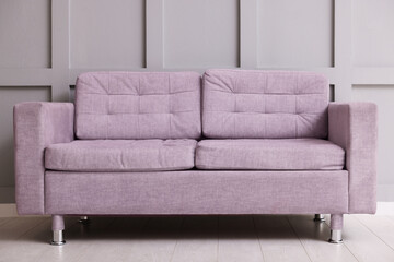 Comfortable violet sofa near gray wall in room