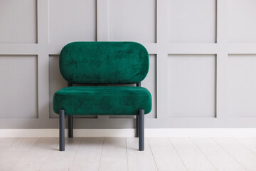 Stylish armchair near gray wall in room. Space for text