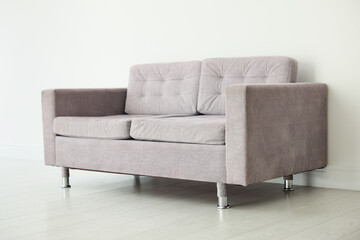 Comfortable gray sofa near white wall in room