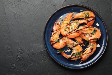 Delicious seafood dish. Tasty grilled shrimps with sauce on black table, top view. Space for text