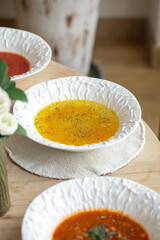 Variety of gourmet soups in textured ceramic bowls on a wooden table in a cozy cafe interior