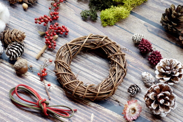 The materials for making Christmas wreaths on the table include cane rings, pine cones and ribbons. Christmas decoration.