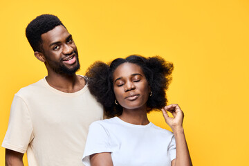 Naklejka premium Happy young couple with natural hairstyles against a bright yellow background, representing love and positivity through vibrant colors and joyful expressions