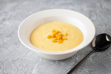Delicious creamy corn soup in ceramic bowl on the table. Vegetarian food