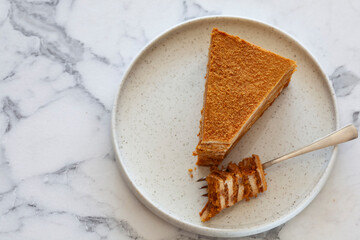 top view of  Slice of delicious layered caramel honey cake served on ceramic plate with place for...