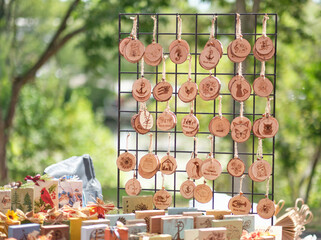  Handmade wooden ornaments. Natural wood with engraved patterns hang on display, surrounded by artisan goods in an outdoor setting with an artisanal atmosphere