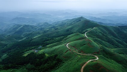 A winding mountain road snakes through lush green hills, showcasing a serene and tranquil landscape.