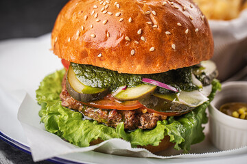 Tasty cheeseburger with fries, sauces and salad on white plate