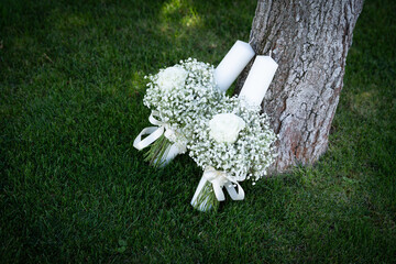 Bridal bouquet made of small white flowers placed on green grass near a tree, symbolising purity, romance and natural elegance