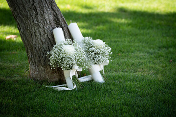 Bridal bouquet made of small white flowers placed on green grass near a tree, symbolising purity, romance and natural elegance