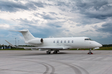 Modern white business jet on the airport on a cloudy day