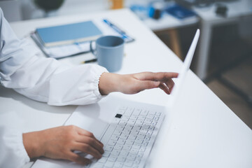 Middle aged female doctor working on laptop in doctor's room