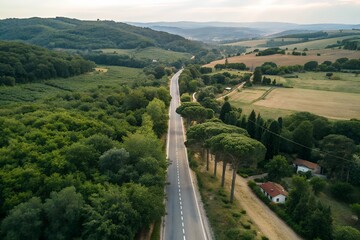 Aerial view of a long straight road winding through lush green tuscan countryside