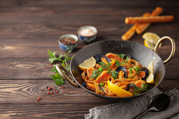 Tagliatelle pasta with mussels and shrimp in the bowl on the table. Mediterranean sea food cuisine