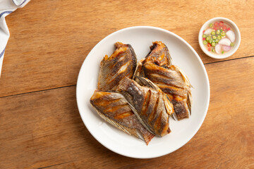 Fried Sun dried tilapia fish in a plate.with fish sauce chili and lime dipping sauce.