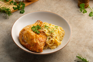 Grilled chicken with carbonara pasta,Air fryer grilled whole chicken leg with fettuccine carbonara sauce in white plate.