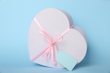 Fototapeta premium Gift box with blank tag on light blue background