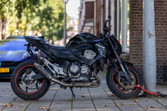 Amsterdam, Netherlands - September 20, 2025: Black Kawasaki motorcycle parked on a street sidewalk secured with a lock
