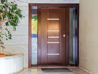 A modern residential apartment building dark brown wood and glass main entrance door.