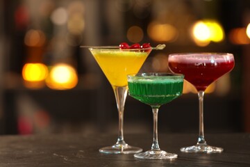 Glasses of alcoholic cocktails on table against blurred background