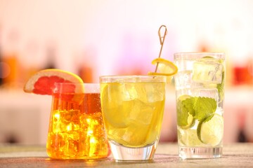 Glasses of alcoholic cocktails on wooden table against blurred background