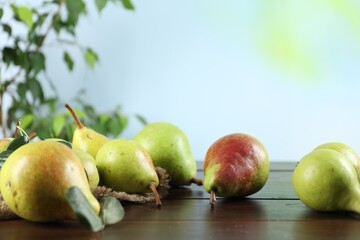 Fresh ripe pears on wooden table and green leaves outdoors, closeup