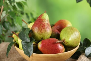 Fresh ripe pears on table and green leaves outdoors, closeup