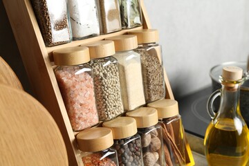 Set of different spices in glass jars and oil on table in kitchen, closeup