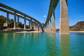 Tranquil scenery under a bridge over a reservoir with crystal clear turquoise water