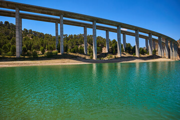 Tranquil scenery under a bridge over a reservoir with crystal clear turquoise water