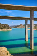 Tranquil scenery under a bridge over a reservoir with crystal clear turquoise water