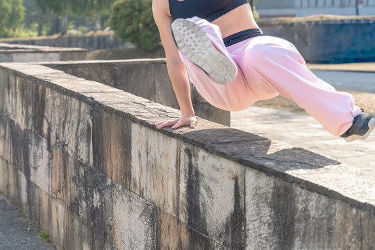 Female athlete performing parkour exercises outdoors, showcasing agility and strength