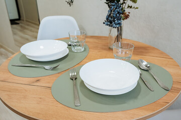 An Elegant Dining Setup featuring pristine White Bowls and sophisticated Glasses arranged beautifully on a charming Wooden Table, creating a warm and inviting atmosphere for meals