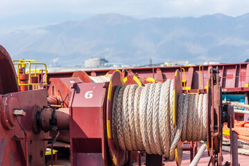 A large mooring winch is installed on the deck of a ship, featuring a massive spool with thick rope...