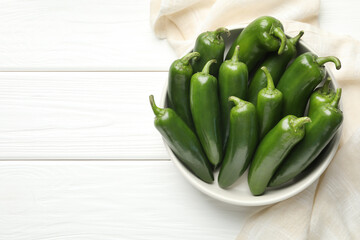 Fresh jalapeno peppers in bowl on white wooden table, above view. Space for text