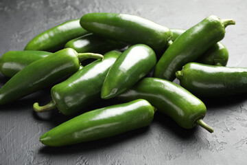 Fresh jalapeno peppers on black textured table, closeup