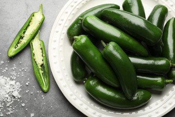 Ripe green jalapeno peppers and salt on grey table, flat lay