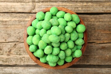 Delicious wasabi coated peanuts in bowl on wooden table, top view