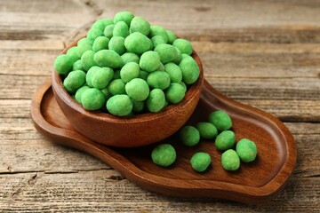 Delicious wasabi coated peanuts in bowl on wooden table, closeup
