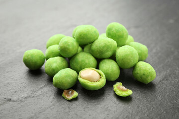 Pile of delicious wasabi coated peanuts on dark textured table, closeup
