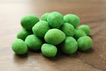 Pile of delicious wasabi coated peanuts on wooden table, closeup