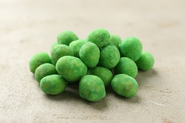 Pile of delicious wasabi coated peanuts on grey textured table, closeup