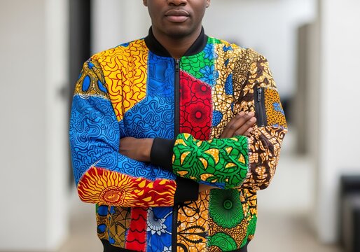 Confident African American man in vibrant patchwork jacket folding arms indoors