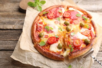 Taking piece of delicious pizza with cheese, tomatoes and olives at wooden table, above view